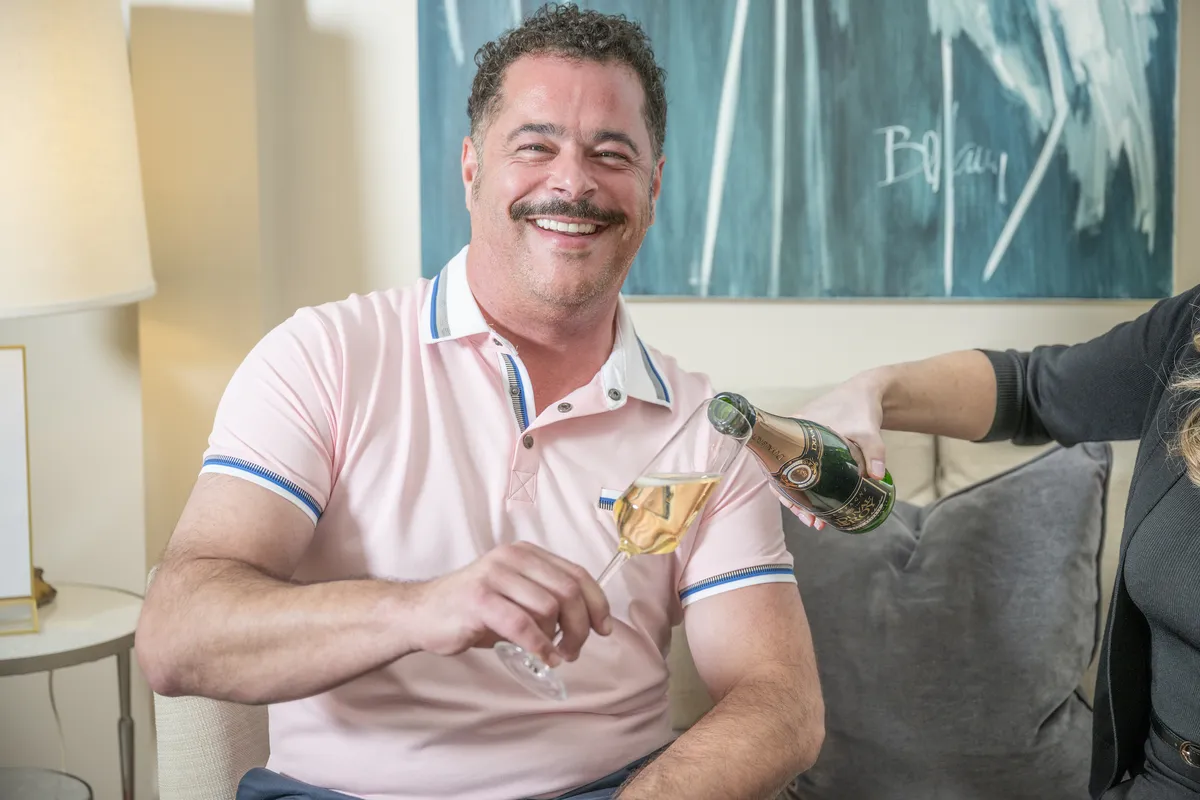 A smiling patient being served a celebratory glass of champagne in the Beyond Exceptional Dentistry lounge